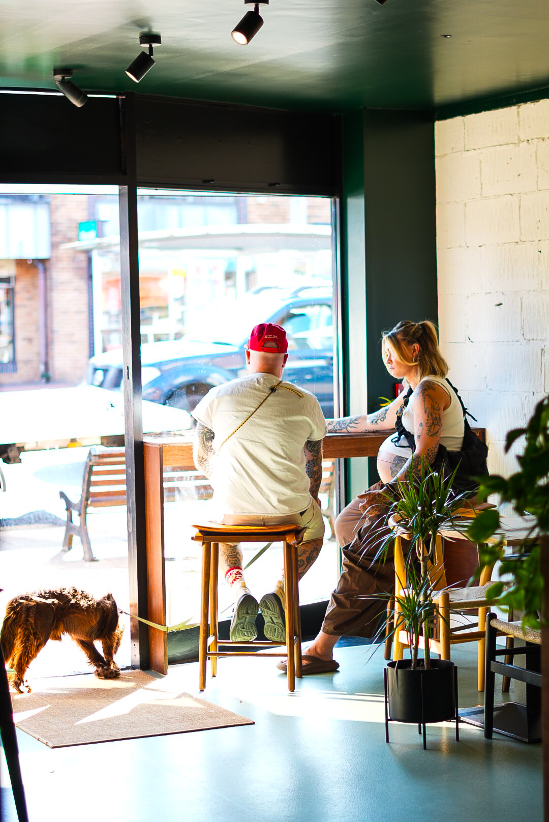 Two customers at the window bar with a dog by the open door