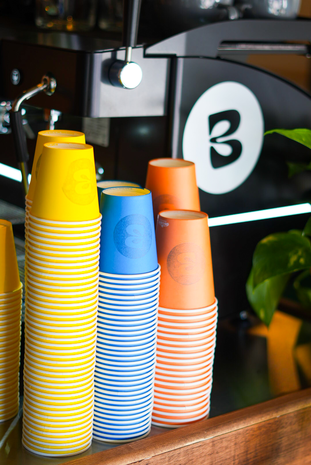 Stacks of yellow, blue and orange Blend cups by the espresso machine
