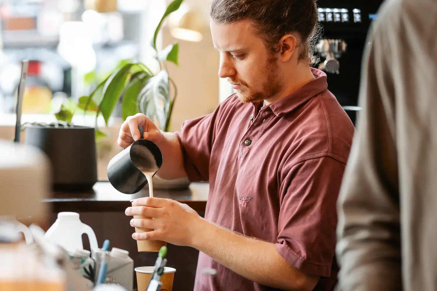 Barista pouring milk into a flat white