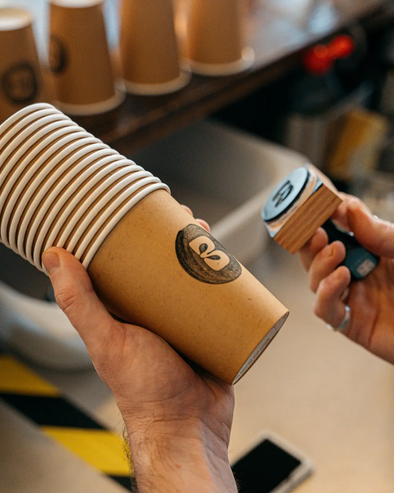 Hand stamping the Blend logo onto a kraft takeaway cup