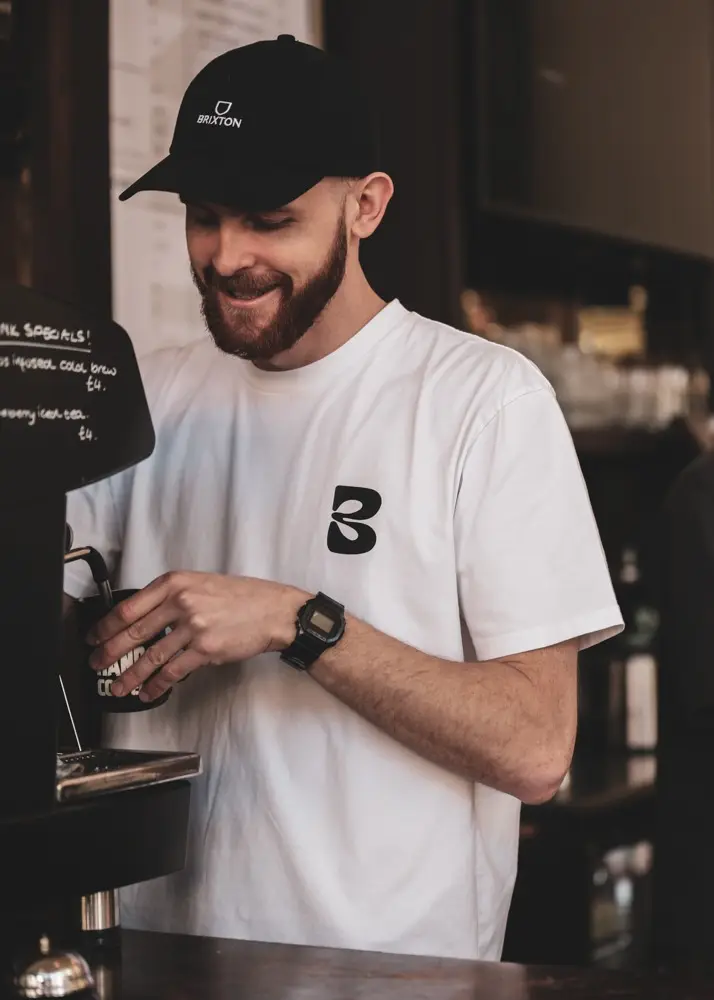 Smiling barista steaming milk at the espresso machine